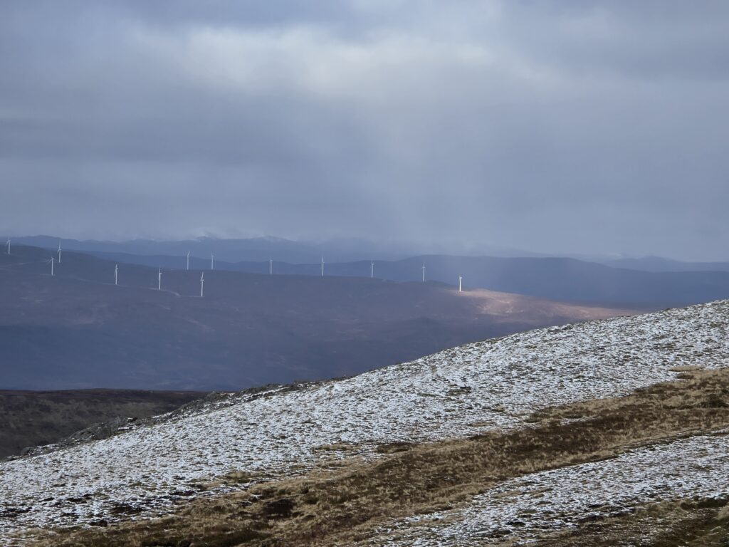 Sunshine shining through the clouds in Scotland with wind turbines in the background.