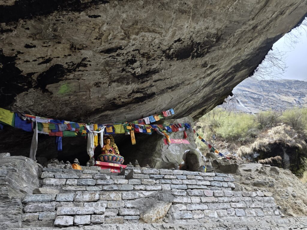 Cave with Buddha statue underneath and prayer flags