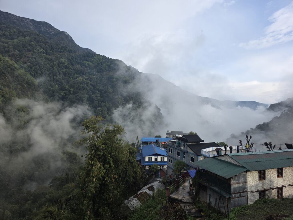 View overlooking the valley from our teahouse overlooking other homes and teahouses with clouds in the sky and valley and swallows flying